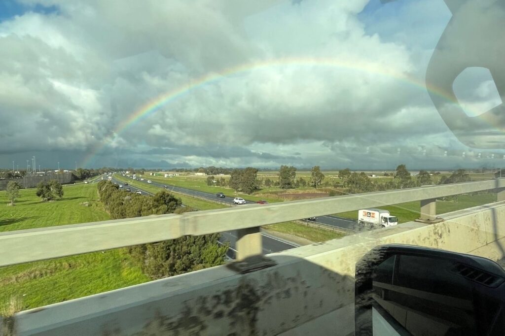 空に虹が架かる車窓風景