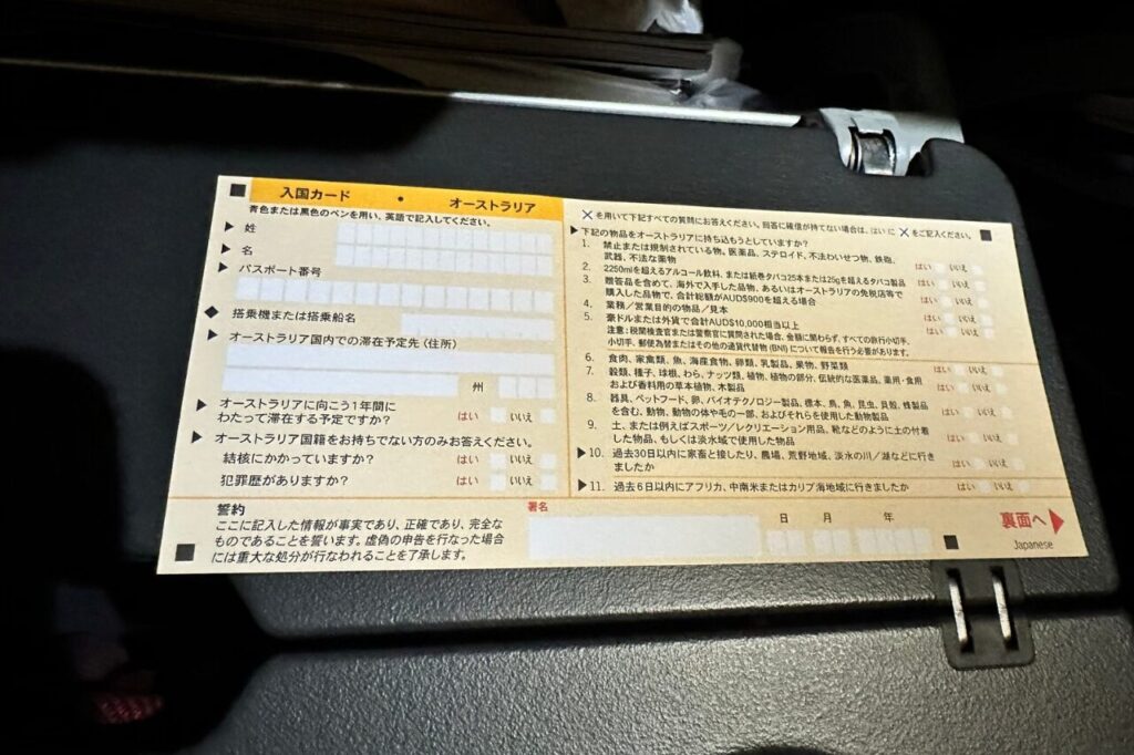 機内のテーブルで入国カードを書く